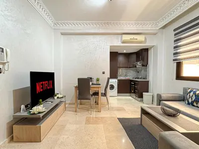 a living room with a couch and a table at Studio moderne avec terrasse, piscine et parking à Guéliz, Marrakech in Marrakech