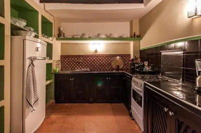 a kitchen with black cabinets and a white refrigerator at Riad XCIX, basin, 3 bedrooms in Medina excluded in Marrakech