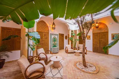 a lobby with a palm tree and chairs and a table at Riad Amskal in Marrakech