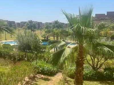 a palm tree in a garden with a pool at Prestigia residences in Marrakech