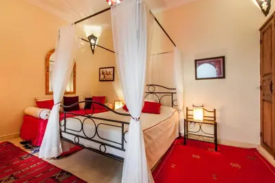 a bedroom with a canopy bed with red pillows at Dar Jena, Rare Riad in Medina on Mamounia in Marrakech