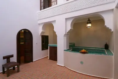 a hallway with a table and a chair in a building at Dar Jena, Rare Riad in Medina on Mamounia in Marrakech
