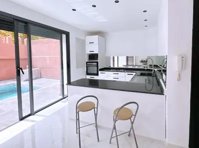 a white kitchen with two stools at a counter at 3 bedroom villa with private pool near centre in Marrakech