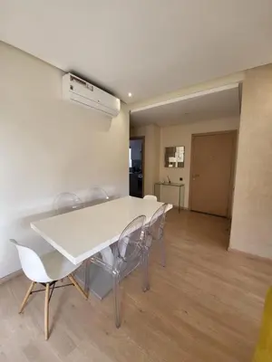 a dining room with a white table and chairs at Appartement familiale 2 chambres Prestigia in Marrakech