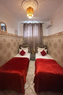 two beds in a hotel room with red sheets at 2 bedroom apartment in heart of Madina in Marrakech