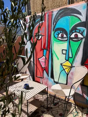 a wall with a mural with two chairs and a table at Riad dar lfen in Marrakech