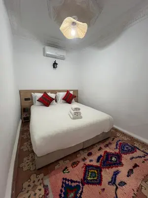 a bedroom with a white bed and a rug at Riad dar lfen in Marrakech