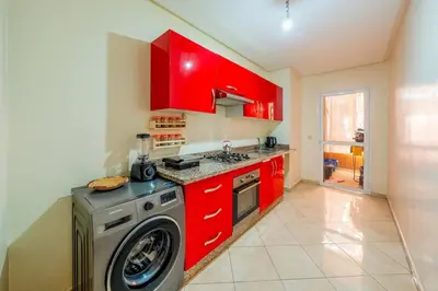 a kitchen with red cabinets and a washing machine at Logement entier Appartement Cosy - Marrakech in Marrakech