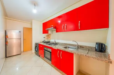 a red kitchen with a sink and a refrigerator at Logement entier Appartement Cosy - Marrakech in Marrakech