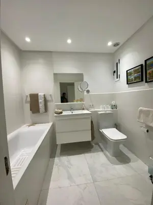 a white bathroom with a tub and a sink and a toilet at Appartement luxe in Marrakech