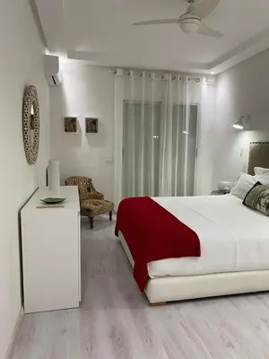 a white bedroom with a large bed with a red blanket at Appartement luxe in Marrakech