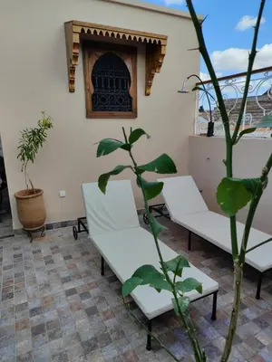 a room with two white chairs and a plant at Dar Manzakin in Marrakech