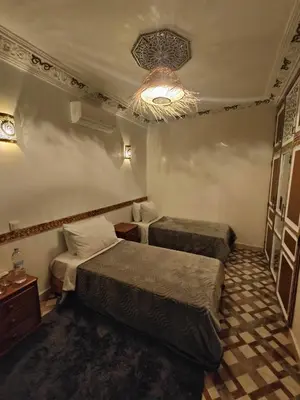 a hotel room with two beds and a chandelier at Dar Manzakin in Marrakech
