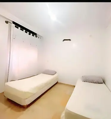 two beds in a room with white walls at سكن امن وهادى in Marrakech