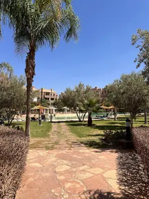 a path in a park with a palm tree at Marrakech Oasis, Residence Ennaim in Marrakech