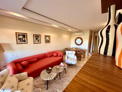 a living room with a red couch and a table at Appartement RDJ - Golf - Piscine - restaurants in Marrakech
