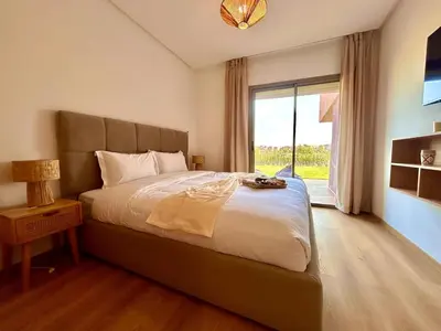 a bedroom with a large bed with a large window at Appartement RDJ - Golf - Piscine - restaurants in Marrakech