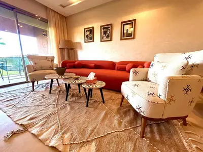 a living room with a red couch and two chairs at Appartement RDJ - Golf - Piscine - restaurants in Marrakech