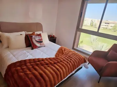 a bedroom with a bed with an orange blanket and a window at Prestigia Luxury Golf-View Escape in Marrakech