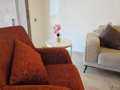 a living room with a couch and a table with a vase of flowers at Prestigia Luxury Golf-View Escape in Marrakech