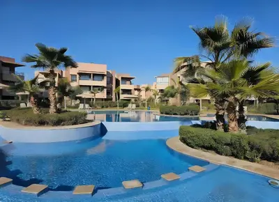 a resort swimming pool with palm trees and buildings at Prestigia Luxury Golf-View Escape in Marrakech