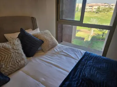 a bed with pillows sitting in front of a window at Prestigia Luxury Golf-View Escape in Marrakech