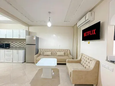 a living room with two couches and a kitchen at 1BR Chic à Izdihar Clim, Wi-Fi & Cuisine Équipée in Marrakech