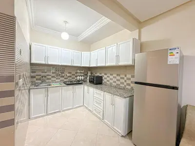 a kitchen with white cabinets and a refrigerator at 1BR Chic à Izdihar Clim, Wi-Fi & Cuisine Équipée in Marrakech