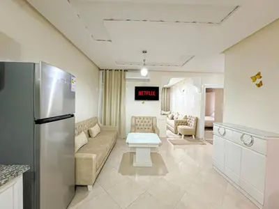 a kitchen and living room with a couch and a refrigerator at 1BR Chic à Izdihar Clim, Wi-Fi & Cuisine Équipée in Marrakech