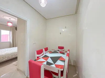 a table and chairs in a room with a bedroom at 1BR Chic à Izdihar Clim, Wi-Fi & Cuisine Équipée in Marrakech