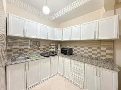 a white kitchen with white cabinets and a microwave at 1BR Chic à Izdihar Clim, Wi-Fi & Cuisine Équipée in Marrakech