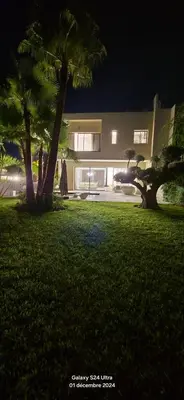 a house with palm trees in a yard at night at villa du golf in Marrakech