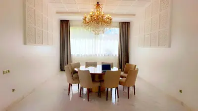 a dining room with a table and chairs and a chandelier at villa du golf in Marrakech