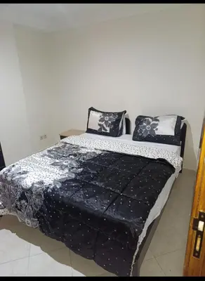 a bed with black and white sheets and pillows at Magnifique appartement in Marrakech