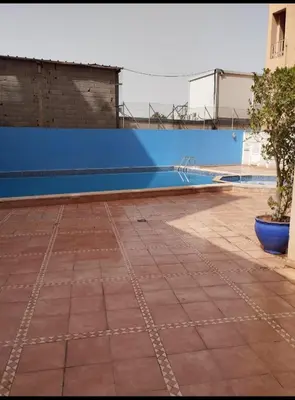 an empty swimming pool with a blue wall at Magnifique appartement in Marrakech
