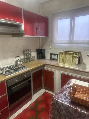 a kitchen with red cabinets and a stove top oven at Appartement Layane 2 chambres 8 mn de gueliz in Marrakech