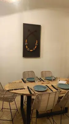a wooden table with chairs and a wreath on a wall at Riad Choubi 3 Bedroom Medina in Marrakech