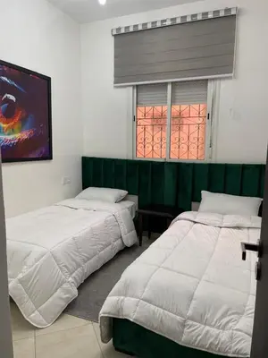 two beds in a bedroom with a green headboard at شقة سكنية للايجار بمراكش in Marrakech