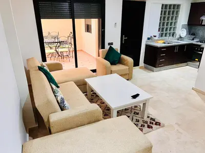 a living room with chairs and a table and a kitchen at Résidence Miramas Gueliz in Marrakech