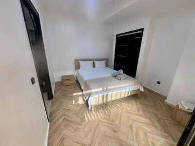 a bedroom with a white bed and a wooden floor at Résidence Miramas Gueliz in Marrakech