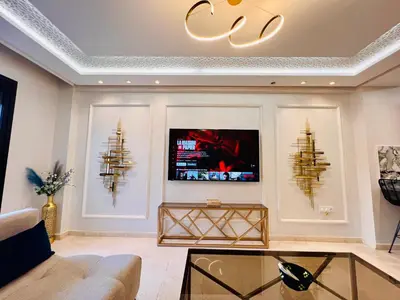a living room with a couch and a tv on a wall at Résidence Miramas Gueliz in Marrakech