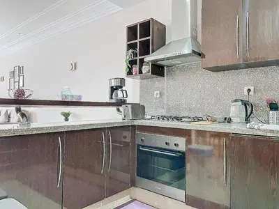 a kitchen with wooden cabinets and a stove top oven at Cosy and spacious apartment in Gueliz in Marrakech