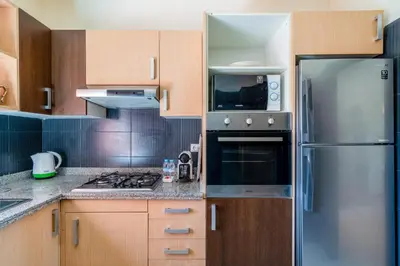 a kitchen with wooden cabinets and a stainless steel refrigerator at Appartement d'Exception-Piscine in Marrakech