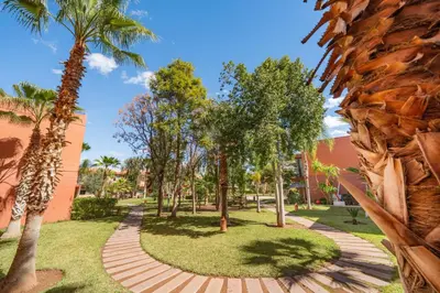 a walkway through a park with palm trees at Appartement d'Exception-Piscine in Marrakech
