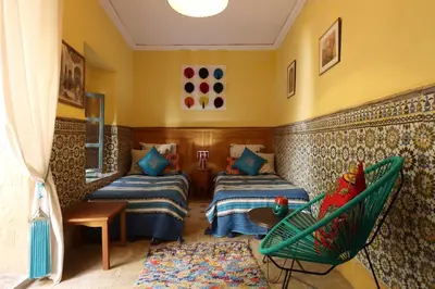 a room with two beds and a green chair at Riad Al Kamar, private, 2 min from Jema El Fna Square in Marrakech