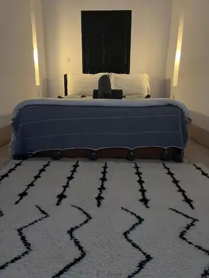 a bedroom with a bed with a rug on the floor at Riad Maiya in Marrakech