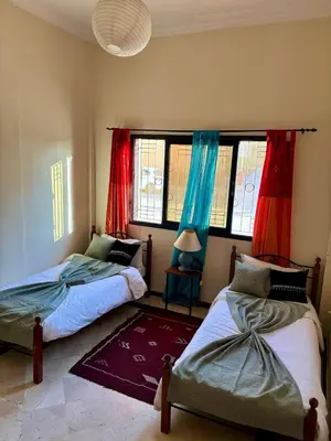 two beds in a room with red and blue curtains at Family residence with a pool in Marrakech