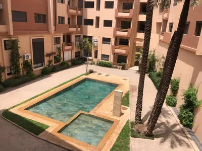 a swimming pool in front of a building with palm trees at marrakech semlalia gueliz in Marrakech