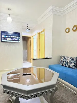 a living room with a blue couch and a glass coffee table at Appartement Calme Parfait & Centre-ville in Marrakech