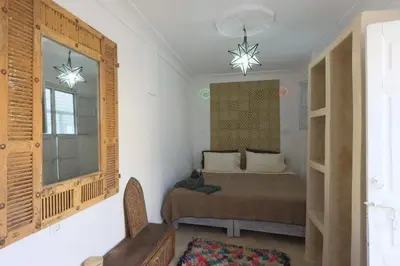 a bedroom with a bed and a window and a chair at Dar Bensuh 2ch privé in Marrakech